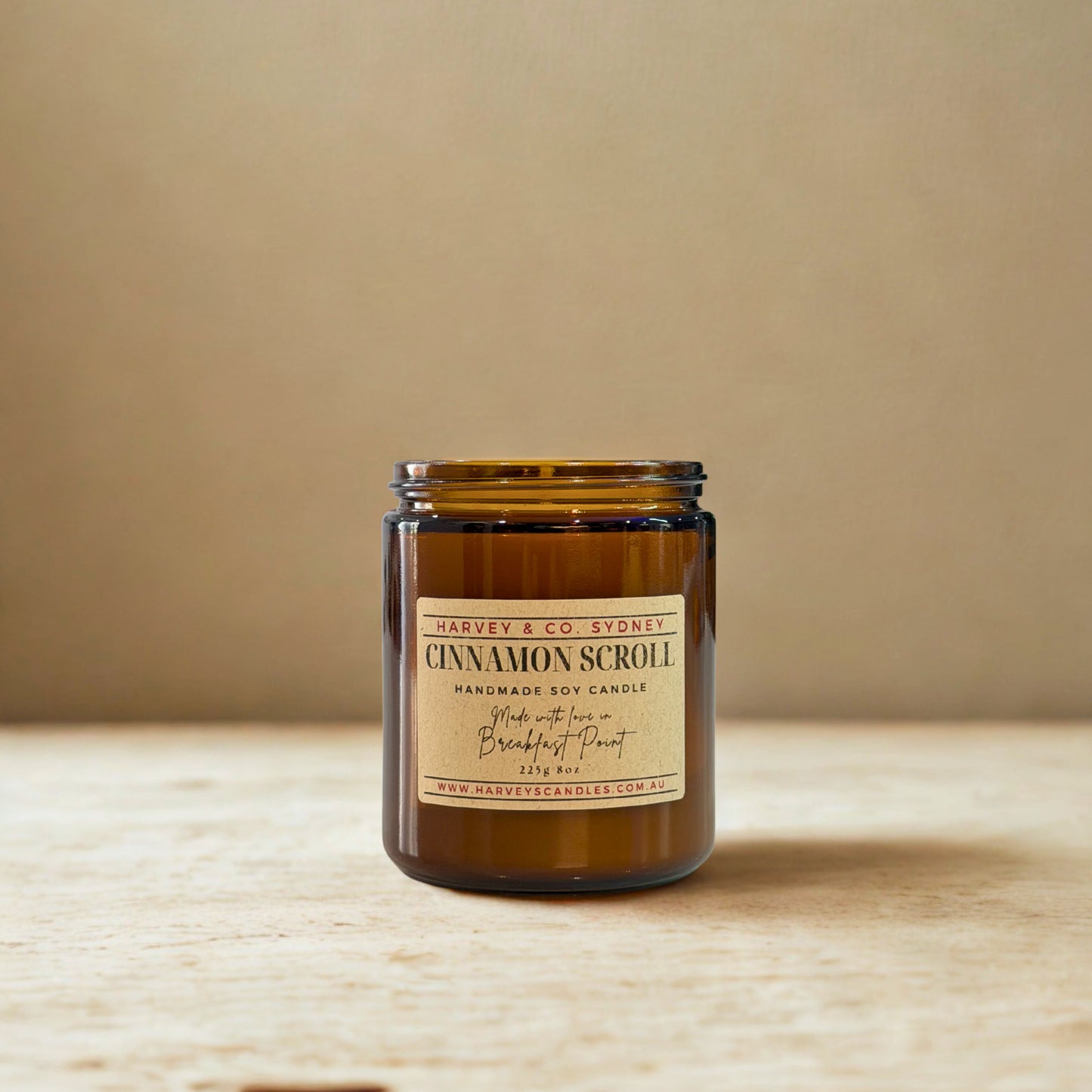 Candle jar labeled 'Cinnamon Scroll' by Harvey & Co. Sydney on a wooden surface with a beige background