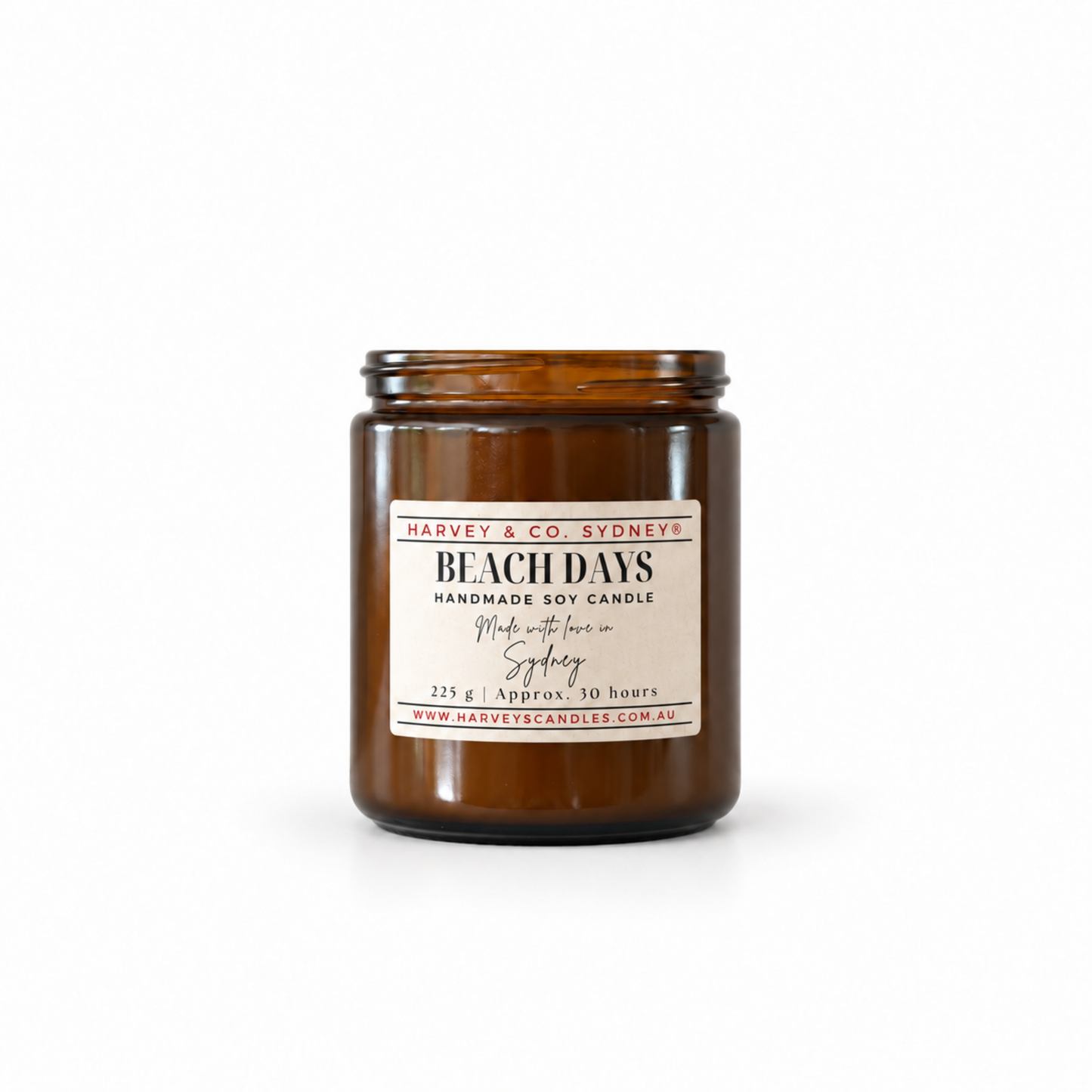 Harvey & Co. Sydney Beach Days soy candle in an amber glass jar with a cream label and red lettering.