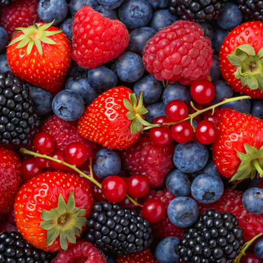 A close-up, top-down view of a dense mix of fresh berries including strawberries, raspberries, blueberries, blackberries, and redcurrants filling the frame.
