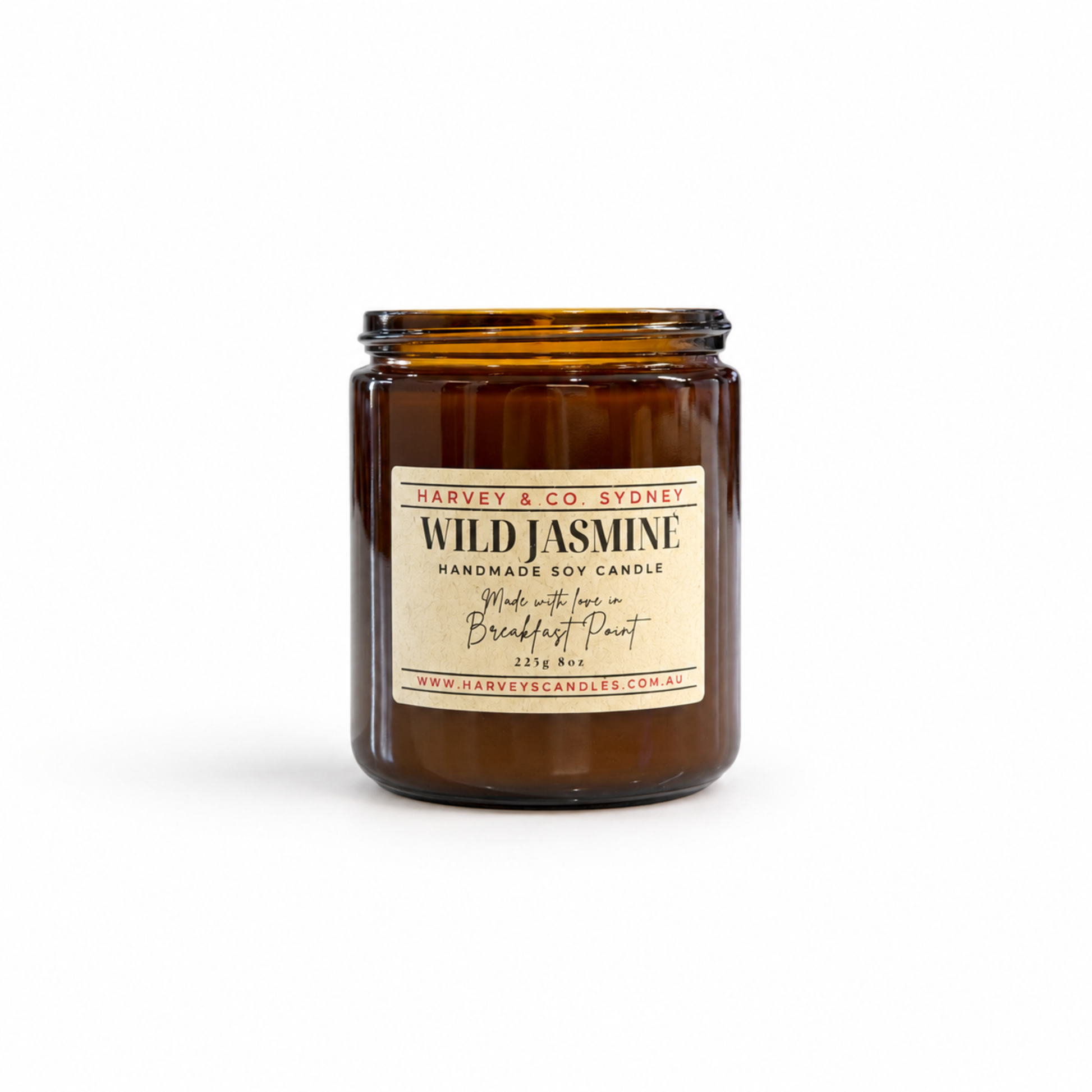 An amber glass jar candle with a cream-colored label reading 'Wild Jasmine' by Harvey & Co. Sydney, set against a plain white background.