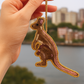 Hand holding a kangaroo-shaped keychain with a cityscape in the background
