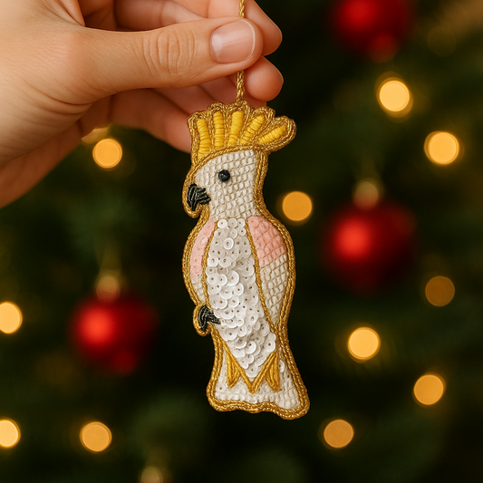 Decorative parrot ornament with a gold crown held in front of a Christmas tree.