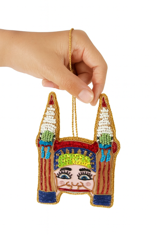 Colorful beaded ornament shaped like a face held by a hand on a white background