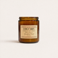 Amber candle jar with a label on a white background