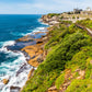 Coastal landscape with ocean, cliffs, and a wooden walkway.