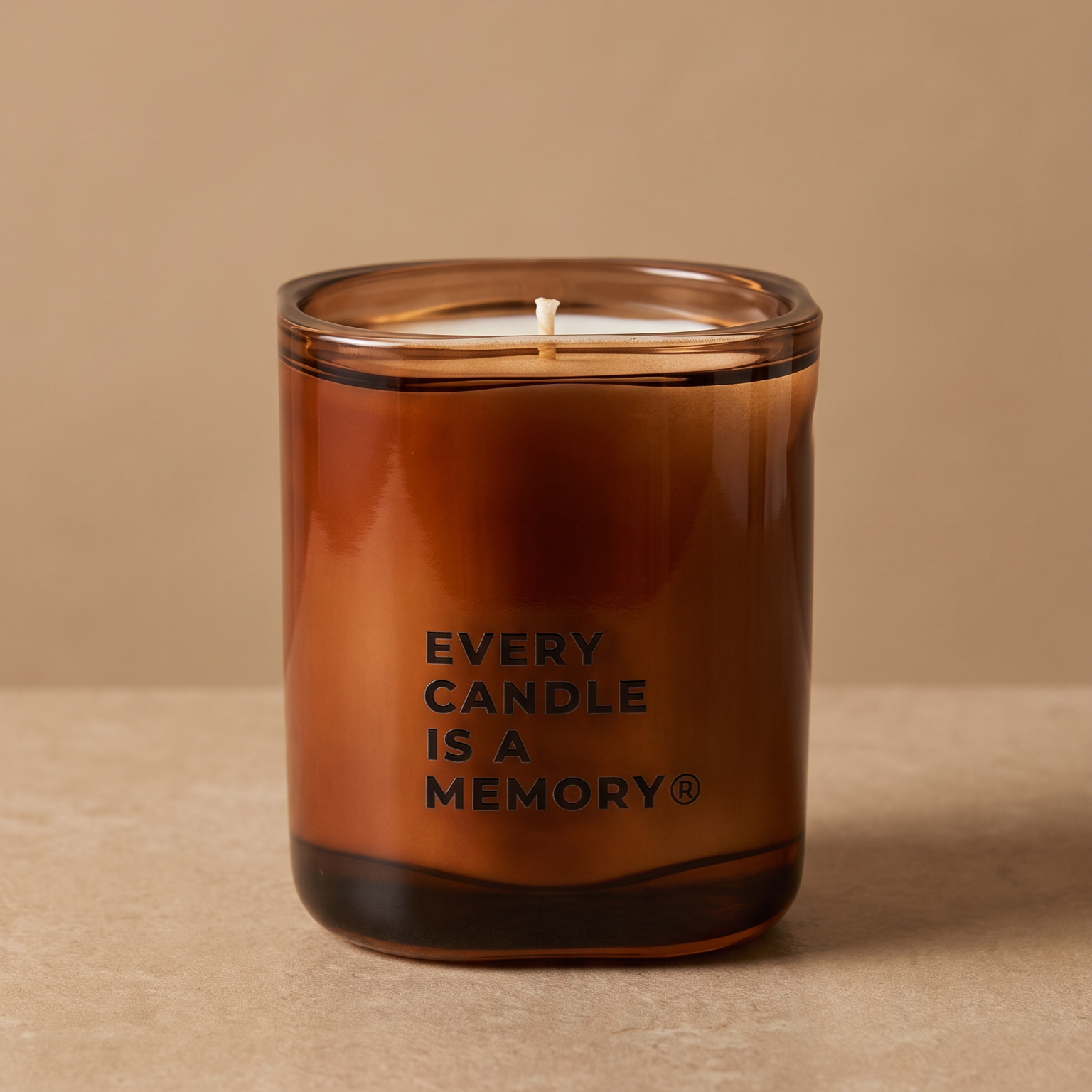 An amber glass jar candle with a single wick and the text 'EVERY CANDLE IS A MEMORY' printed on the front, set against a warm beige background.