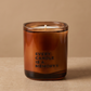 An amber glass jar candle with a single wick and the text 'EVERY CANDLE IS A MEMORY' printed on the front, set against a warm beige background.