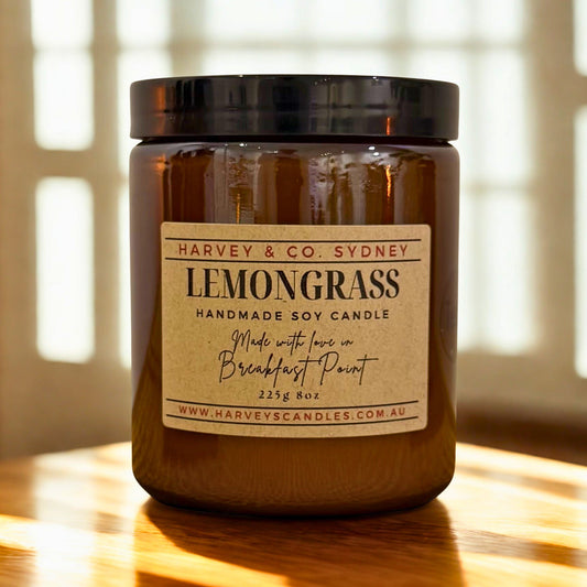 Harvey & Co. Sydney lemongrass candle on a wooden surface with sunlight filtering through blinds.