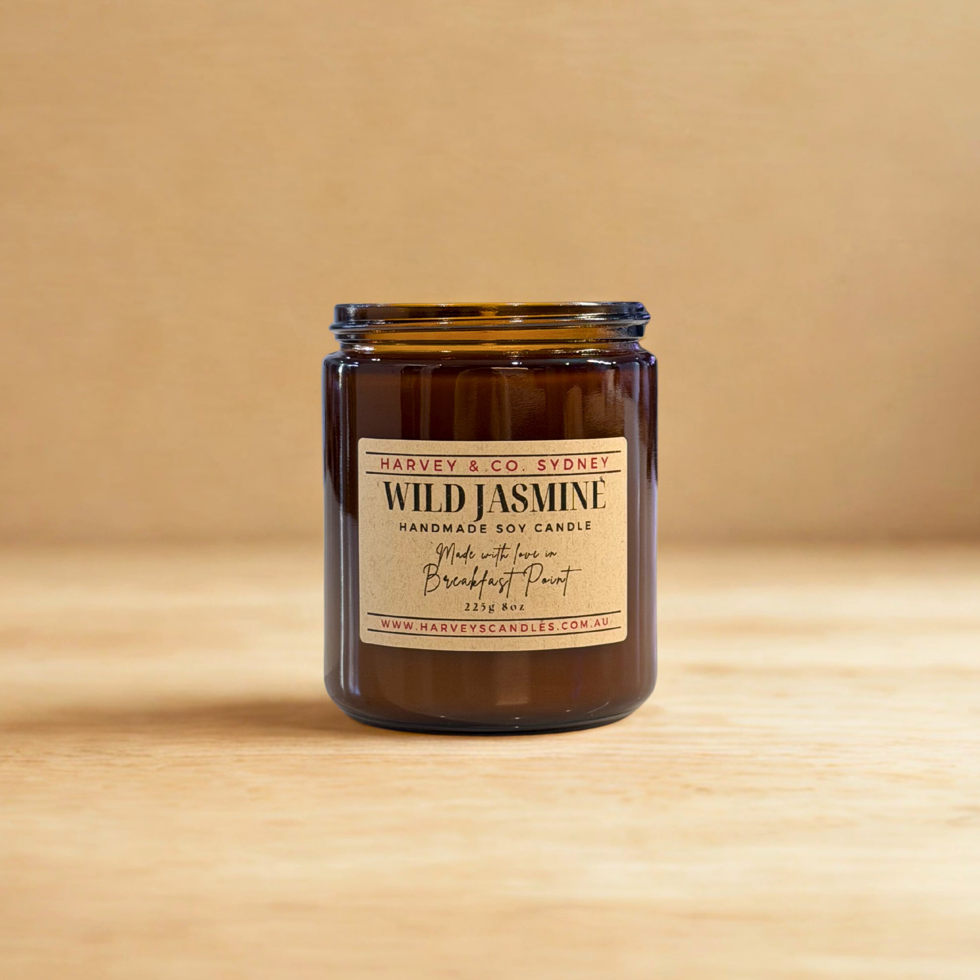 Jar of Wild Jasmine candle with a label on a wooden surface and beige background