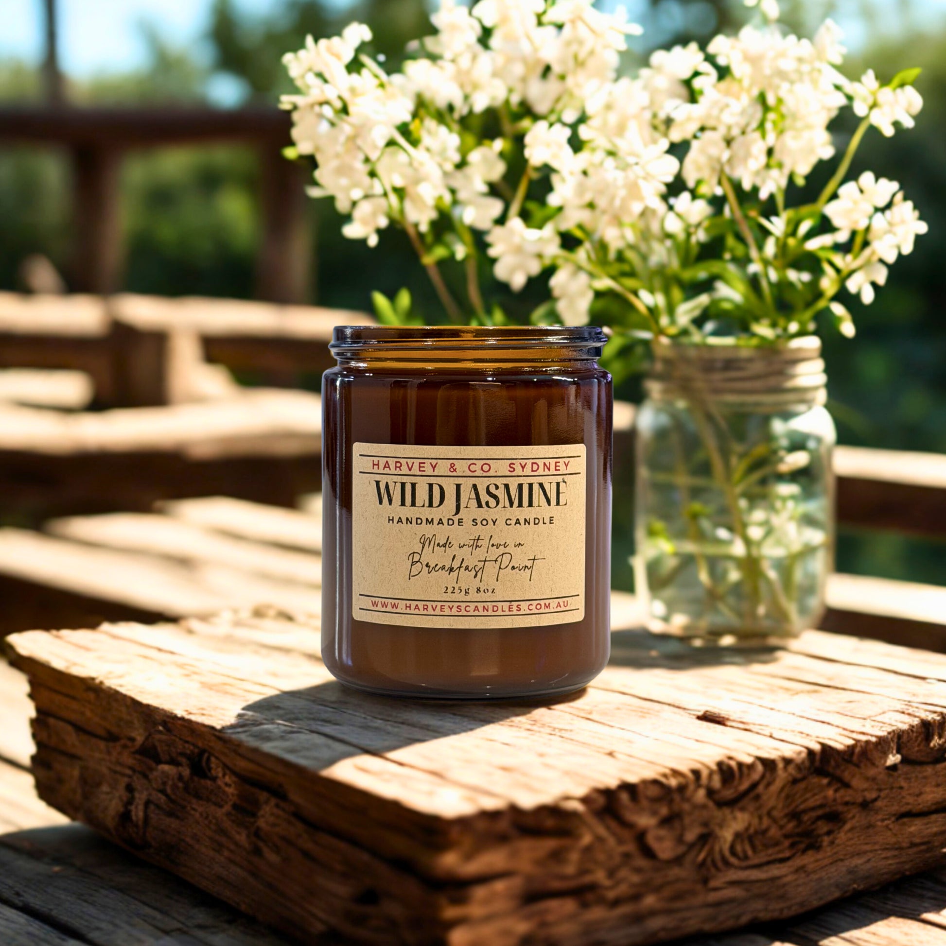 Harvey & Co. Sydney Wild Jasmine candle on a wooden surface with flowers in the background
