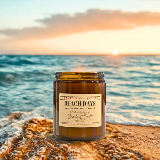 Candle labeled 'Beach Days' by Harvey & Co. Sydney on a beach with sunset in the background