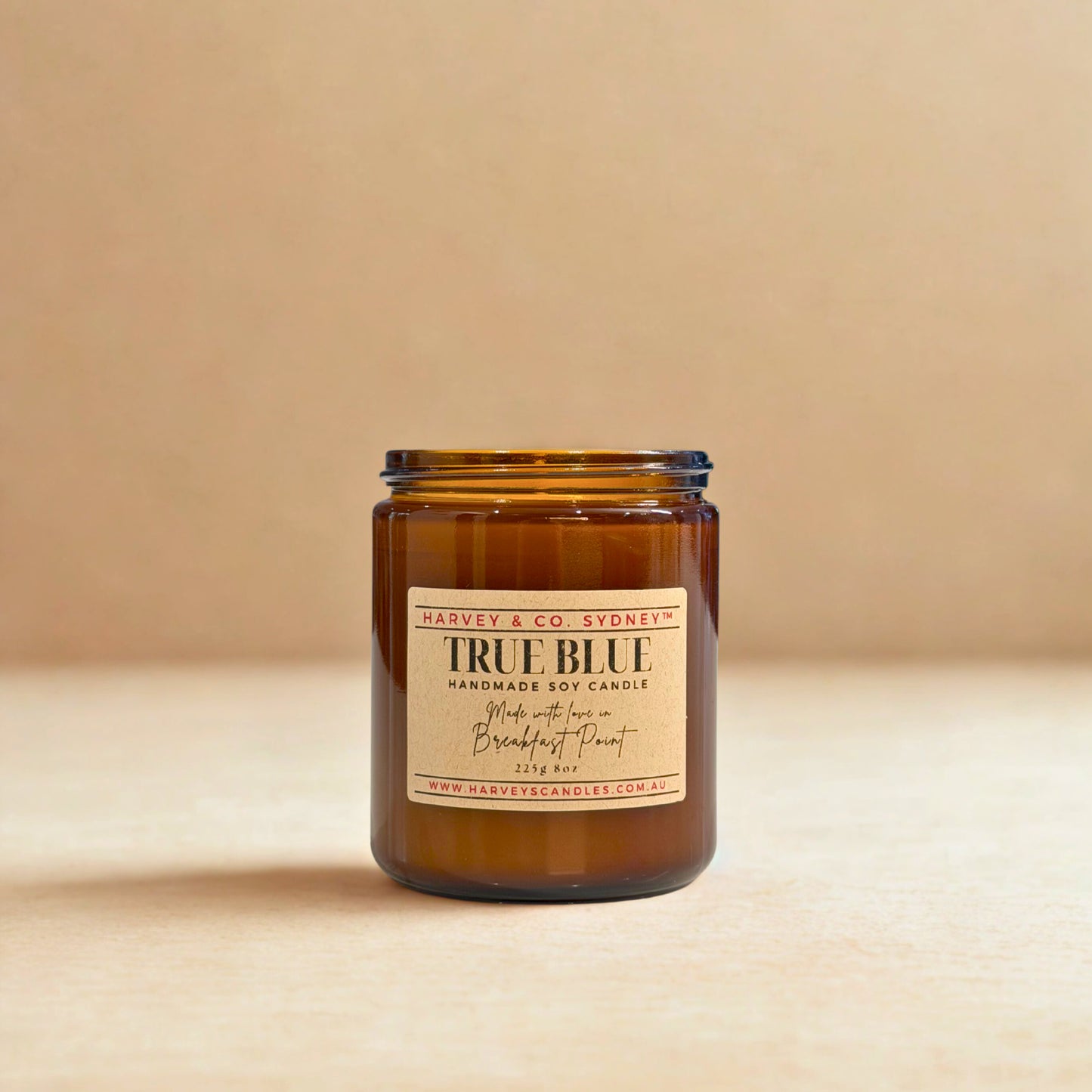 Amber glass candle with a label on a beige background