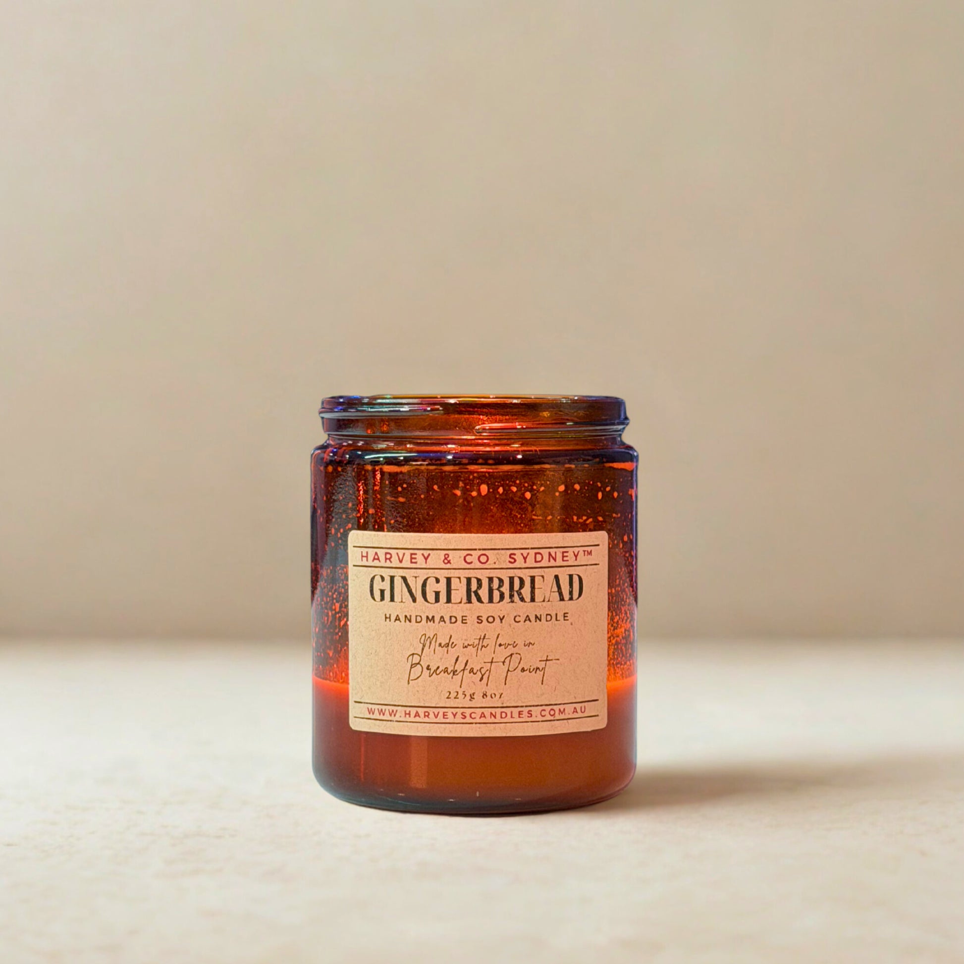 Gingerbread scented candle in an amber jar with a beige label on a beige background