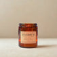 Gingerbread scented candle in an amber jar with a beige label on a beige background
