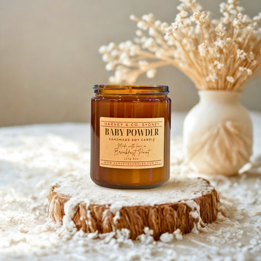 Candle labeled 'Baby Powder' by Harvey & Co. Sydney on a wooden coaster with decorative elements.