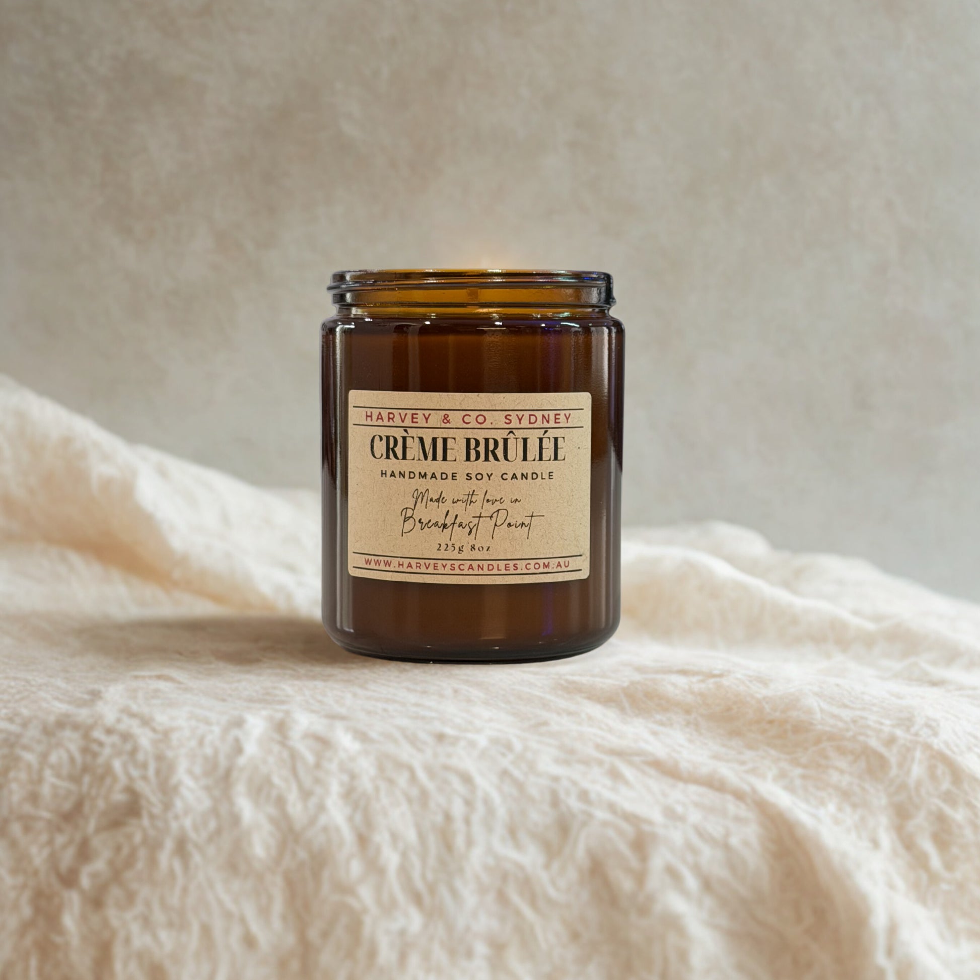 Candle labeled 'Creme Brulee' by Harvey & Co. Sydney on a soft fabric background
