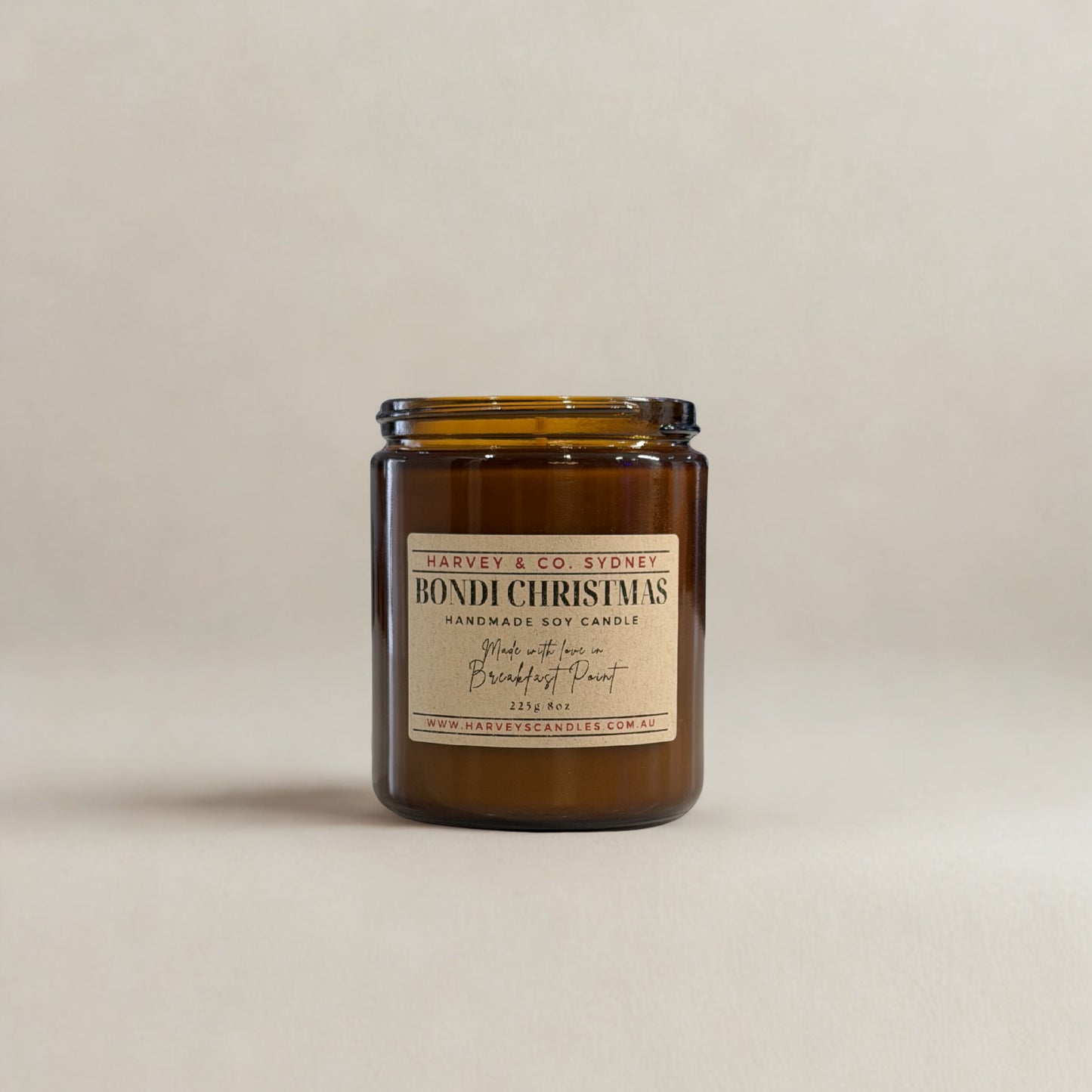 Amber glass candle with a label on a beige background