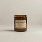 Amber glass candle with a label on a beige background
