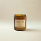 Brown candle jar with a label on a beige background