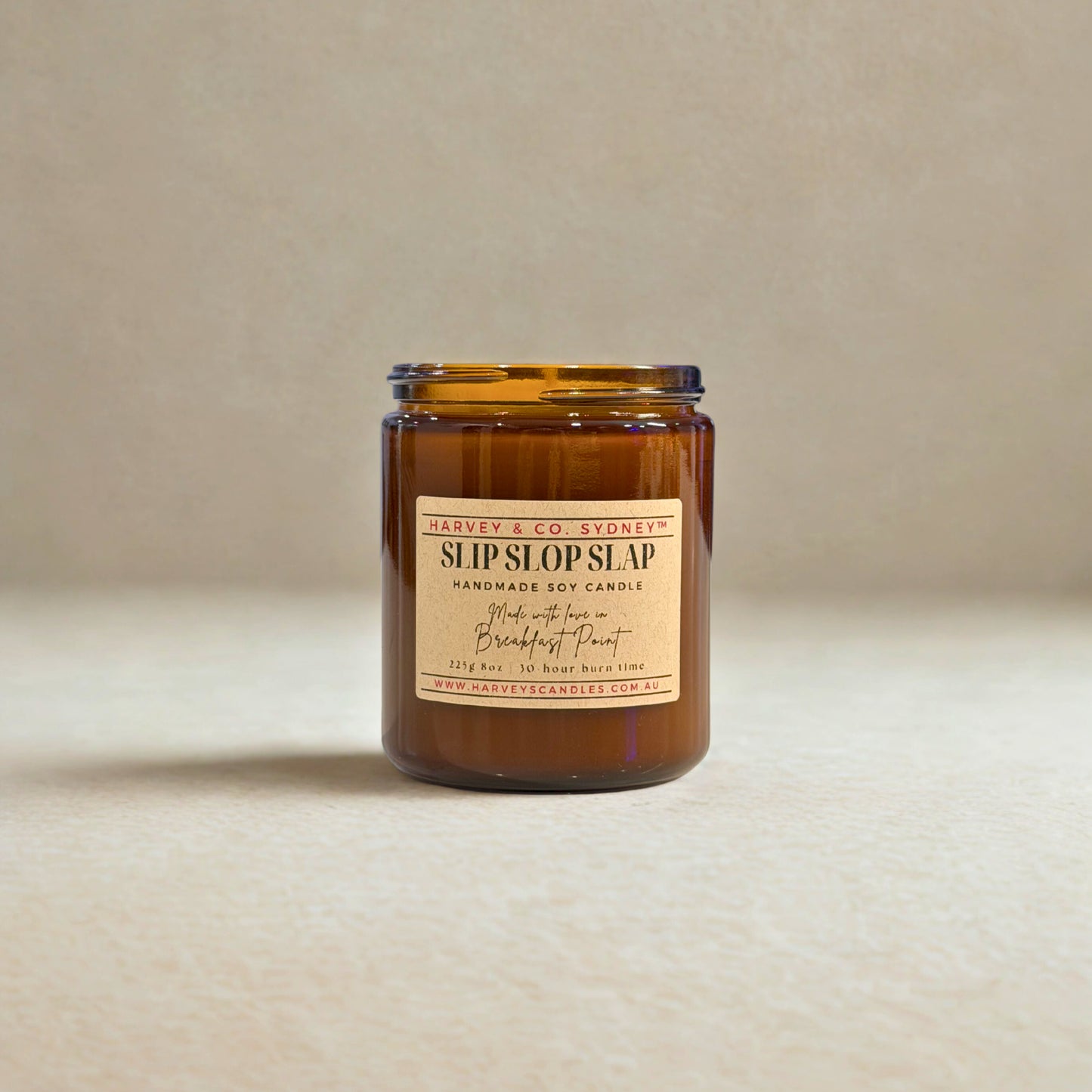 Amber glass candle with a label on a beige background