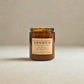 Amber glass candle with a label on a beige background