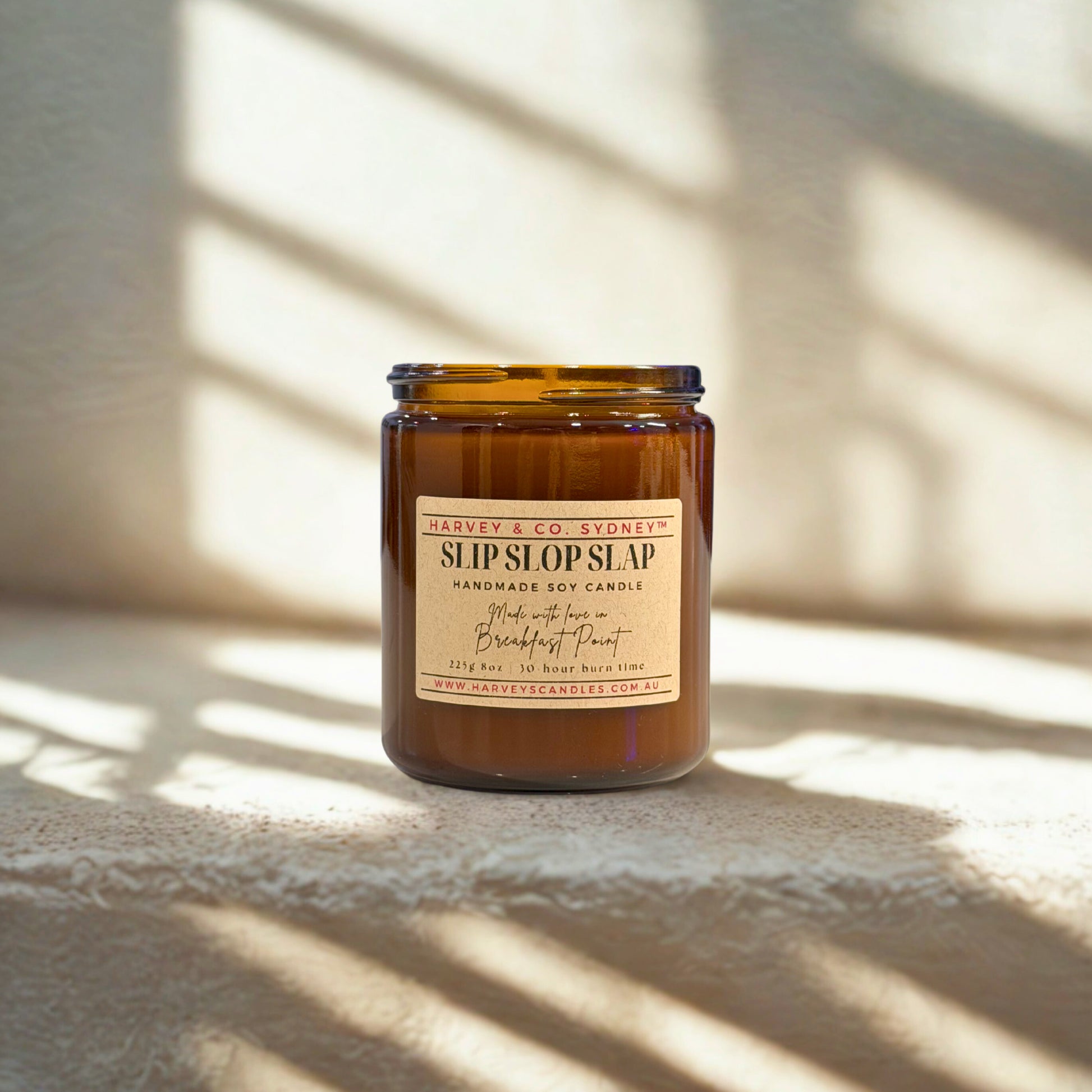 Brown candle jar with label on a textured surface with light shadows