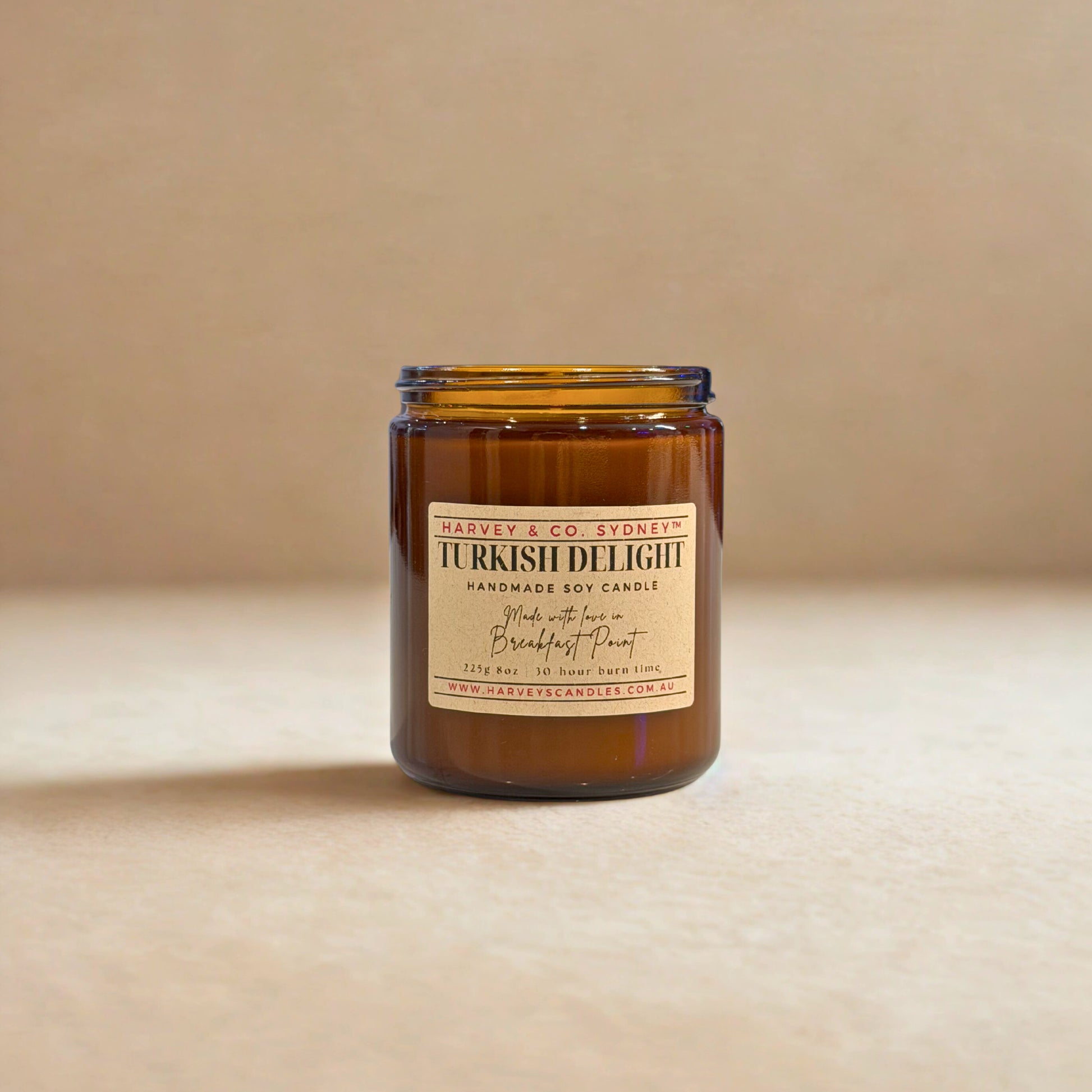 Amber glass candle with a label on a beige background