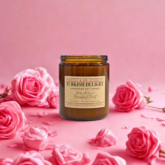 Candle labeled 'Turkish Delight' surrounded by pink roses on a pink background