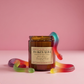 Jar of 'Snakes Alive' candle with gummy worm decorations on a pink background