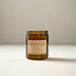 Amber glass candle with a label on a neutral background