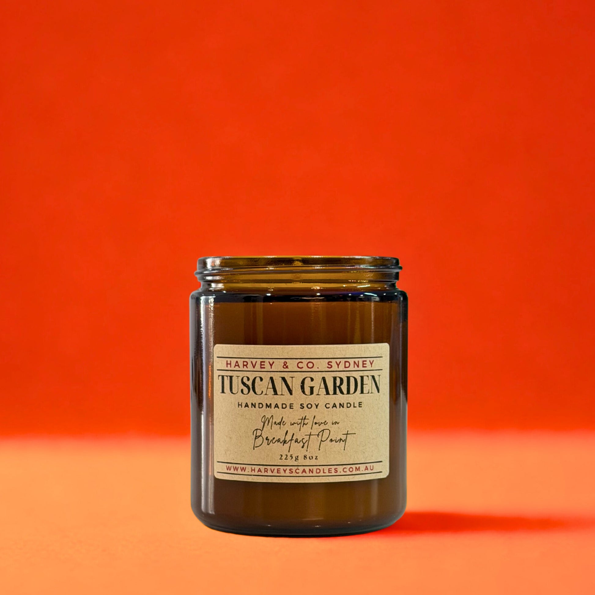 Candle in a glass jar with a label on an orange background
