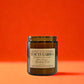 Candle in a glass jar with a label on an orange background