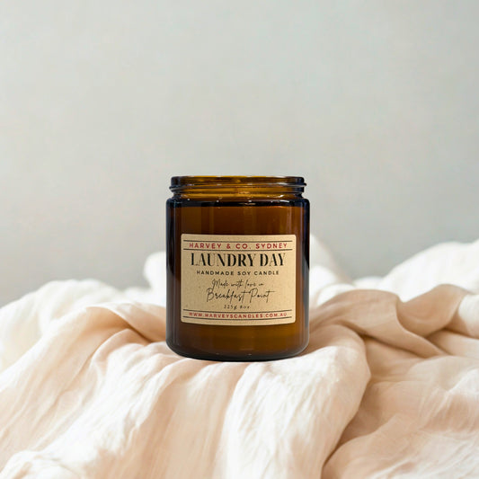 Brown candle labeled 'Laundry Day' on a soft fabric background