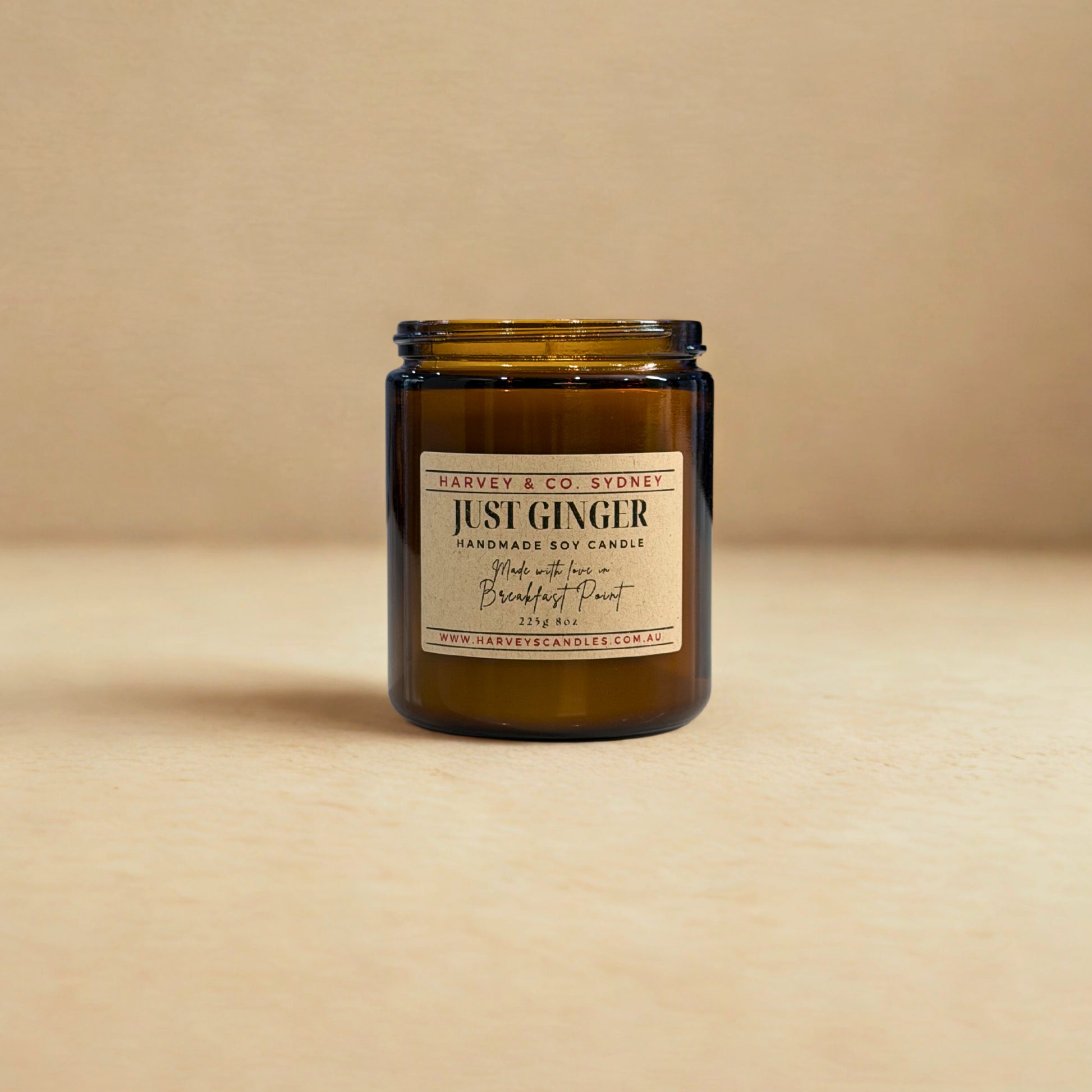 Handmade soy candle in an amber jar with a label on a beige background