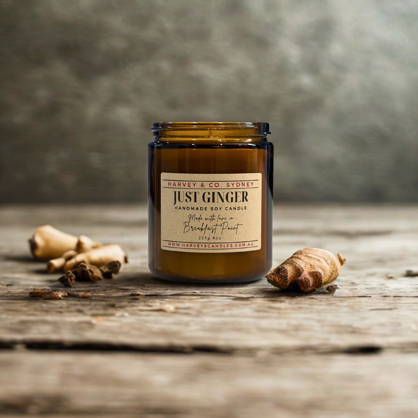 Handmade soy candle labeled 'Just Ginger' by Harvey & Co. Sydney on a wooden surface with ginger roots.