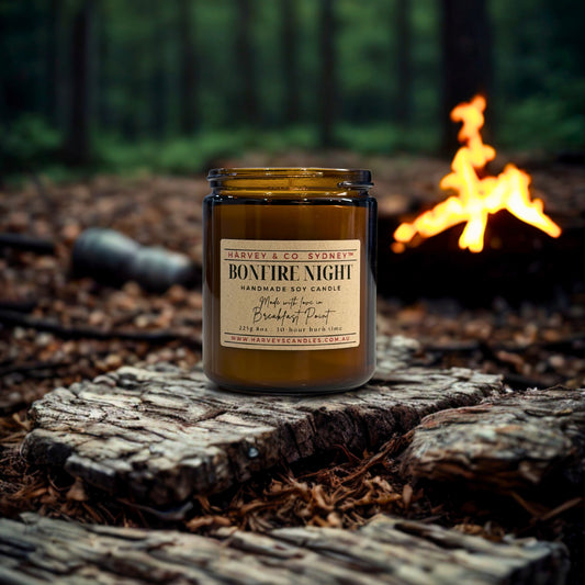 Candle labeled 'Bonfire Night' on a wooden stump with a campfire in the background