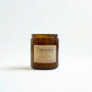 Amber glass candle jar with a label on a white background