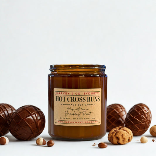 Brown candle jar with 'Harvey & Co. Sydney' label surrounded by chocolate Easter eggs and cookies on a light background