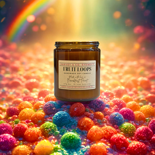 Jar of 'Fruit Loops' candle surrounded by colorful candy balls with a rainbow in the background