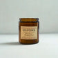 Amber glass candle with a label on a light gray background