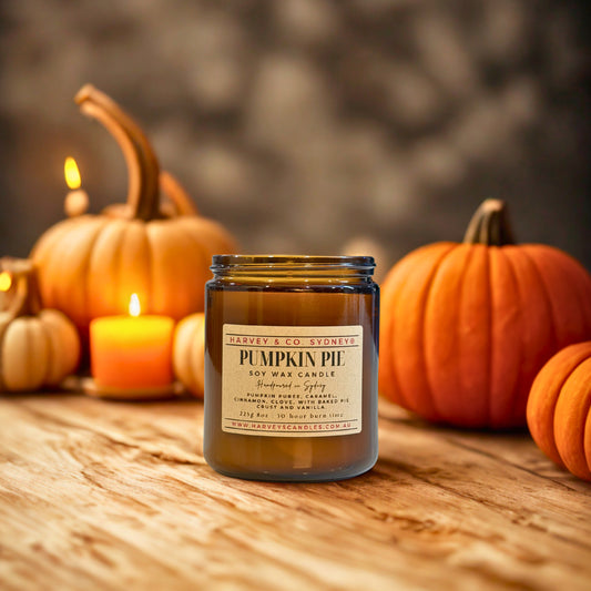 Pumpkin pie candle with pumpkins and candles on a wooden surface