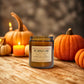 Pumpkin pie candle with pumpkins and candles on a wooden surface