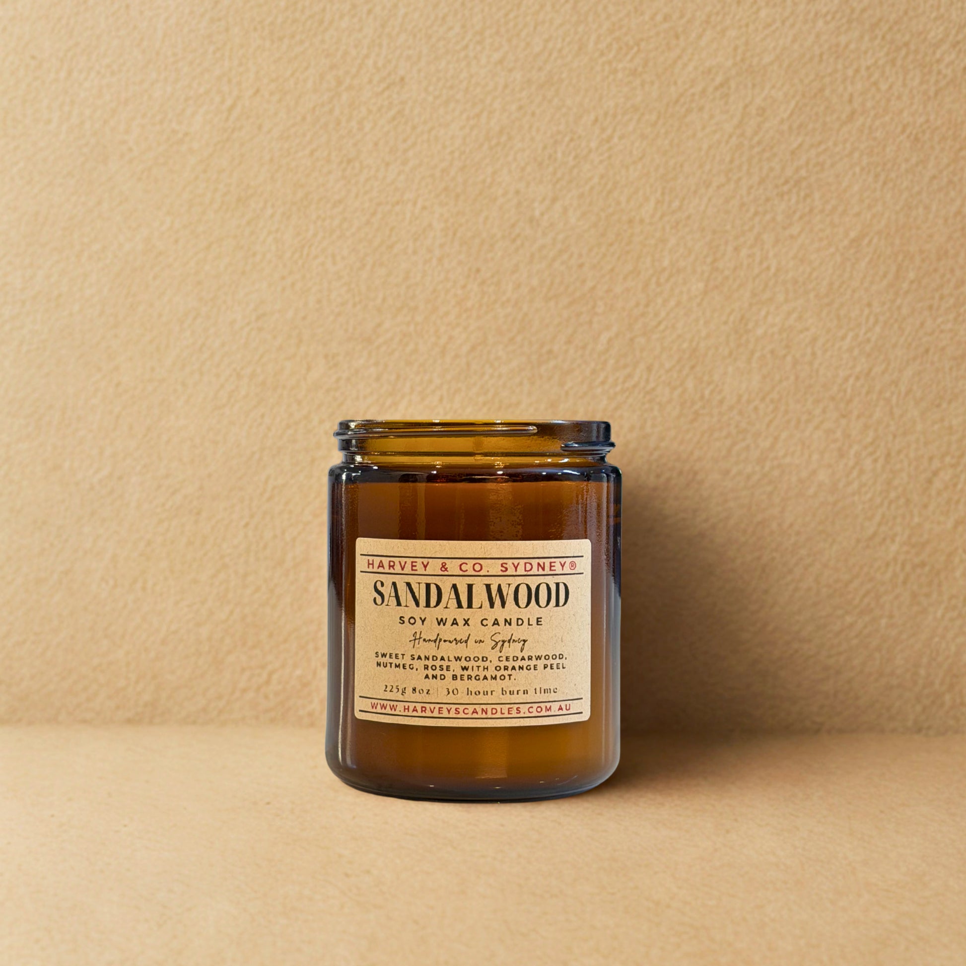 Sandalwood candle in a glass jar with a label on a beige background