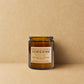 Sandalwood candle in a glass jar with a label on a beige background