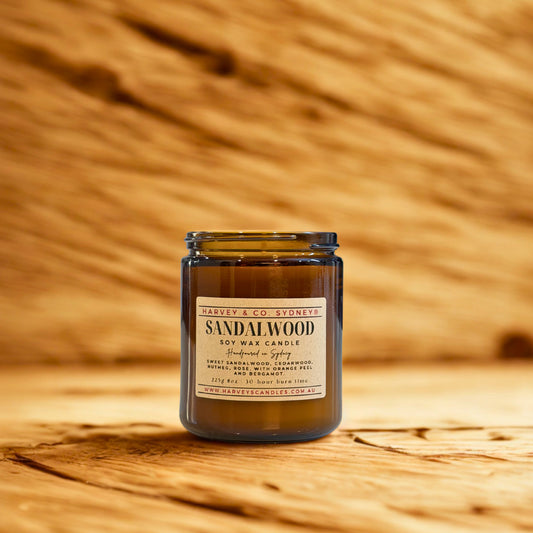 Sandalwood candle in a glass jar with a label on a wooden background