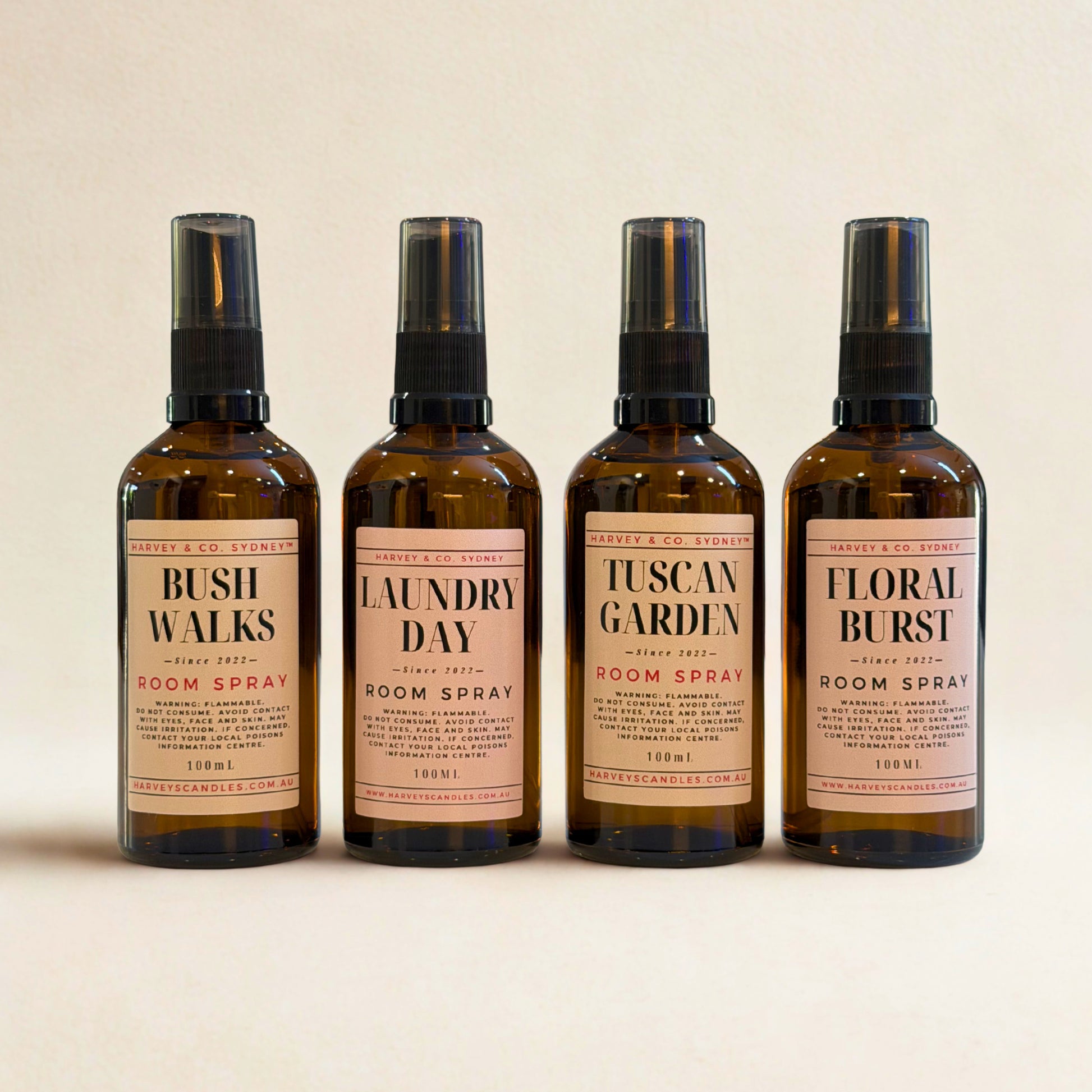 Four bottles of room spray with labeled scents on a beige background