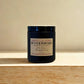 Black candle labeled 'Butter Popcorn' by Harvey & Co. Sydney on a wooden surface with a beige background.