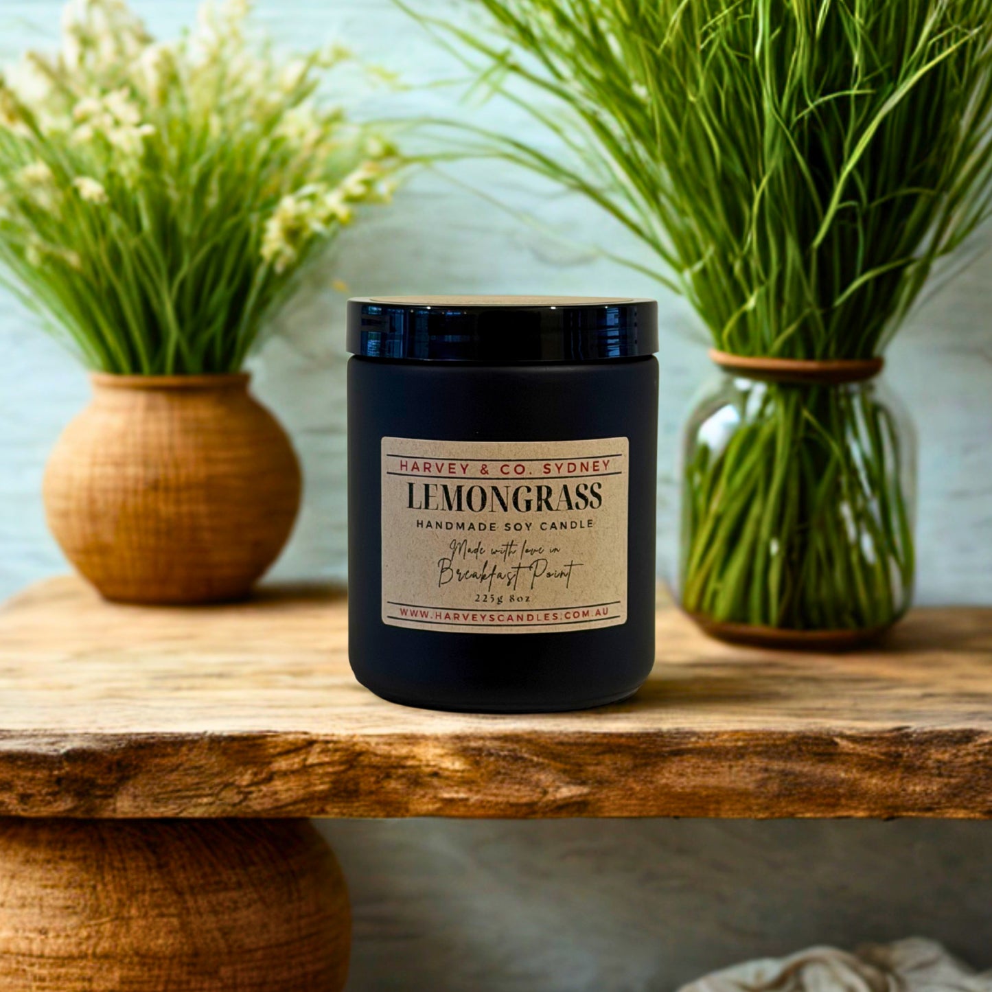 Harvey & Co Sydney lemongrass candle on a wooden surface with plants in the background