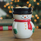 Snowman-shaped mug with a red scarf against a blurred Christmas tree background