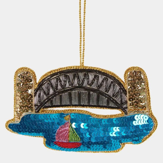 Decorative ornament shaped like a bridge with a sailboat on water, featuring gold and blue colors.